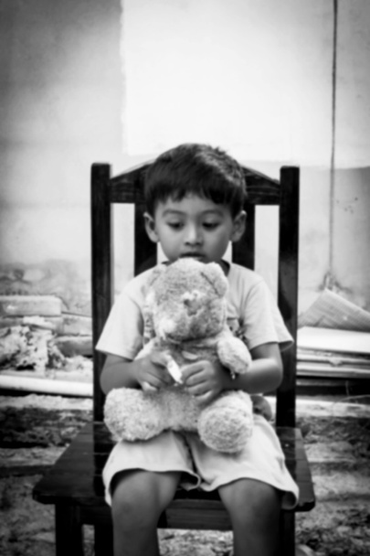 Θολές από μικρό αγόρι κάθεται μόνος σε καρέκλα, μαύρο και άσπρο - Φωτογραφία, εικόνα