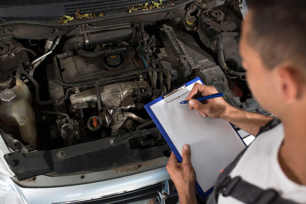 Mechanik, sprawdzanie listy części samochodowych - Zdjęcie, obraz