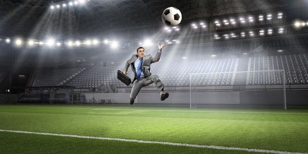 Businessman kicking ball . Mixed media - Foto, Imagen