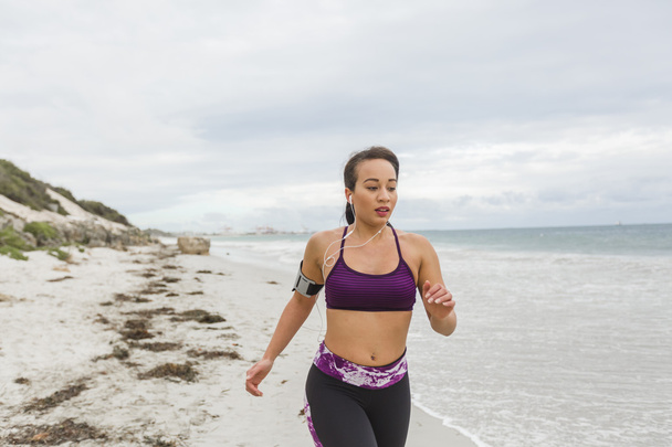 Female runner jogging during outdoor workout on the beach - Φωτογραφία, εικόνα
