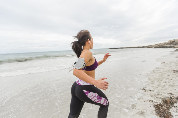 Female runner jogging during outdoor workout on the beach - Photo, image