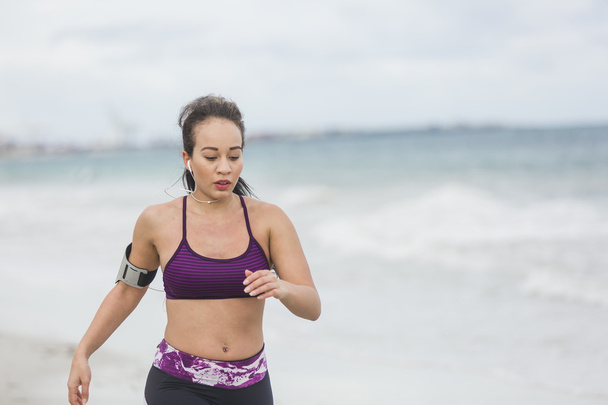 Fitness Woman finishing work out by the Ocean at cloudy winter day - Photo, image
