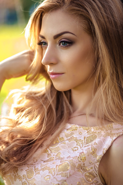 beautiful young woman in a summer dress near blooming trees - Fotografie, Obrázek