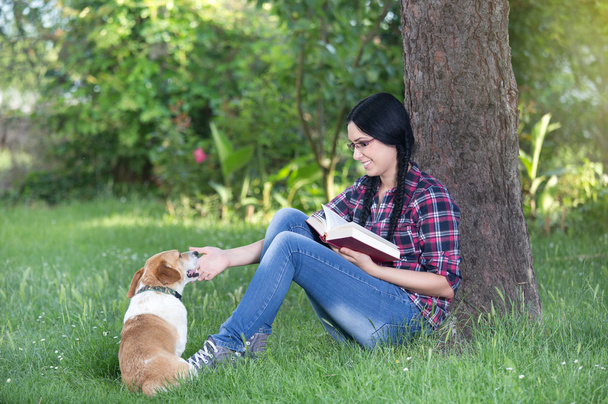 Κορίτσι με το σκυλί στο γρασίδι, διαβάζοντας ένα βιβλίο - Φωτογραφία, εικόνα