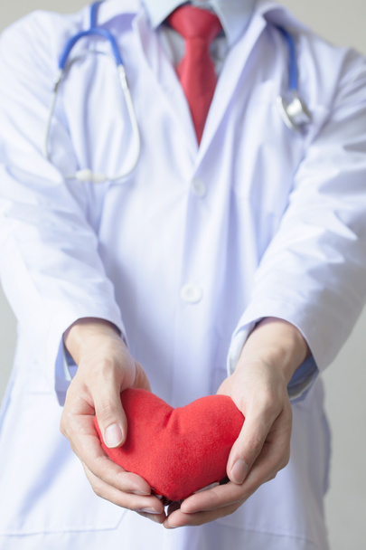 Doctor giving a heart shape object in white isolated background - Photo, Image