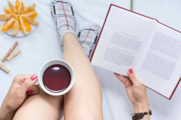 Woman reading a book and having cup of tea - Photo, Image