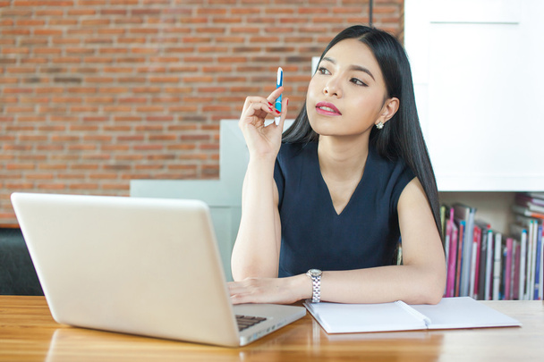 Mujer asiática pensando y trabajando en la oficina moderna
 - Foto, imagen