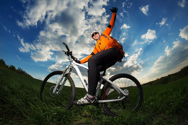 Young man riding on bicycle through deep grass with backpack - Foto, Imagem