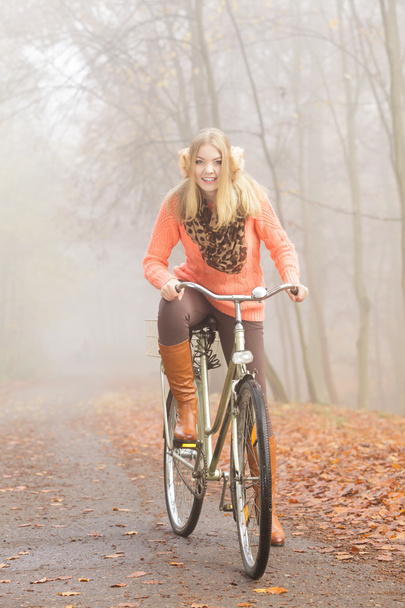 Active woman riding bike in autumn park. - Valokuva, kuva