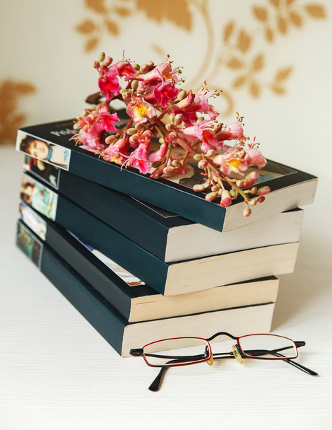 O ramo da castanha-de-rosa está na pilha de livros com óculos na mesa branca, foco seletivo
 - Foto, Imagem