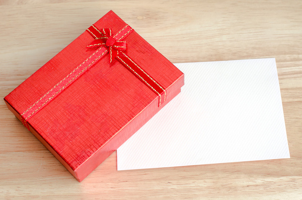 Red gift box and blank white card on wooden table - 写真・画像