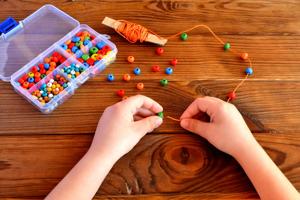 Niños manos sosteniendo cuentas y cordón. Bebé sensorial juego
  - Foto, Imagen