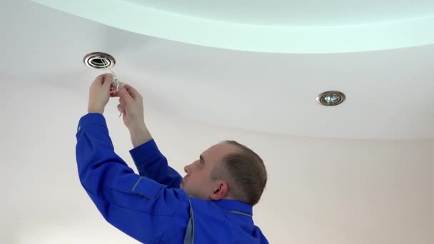 працівник встановлює або замінює галогенну лампу в стелю
 - Кадри, відео