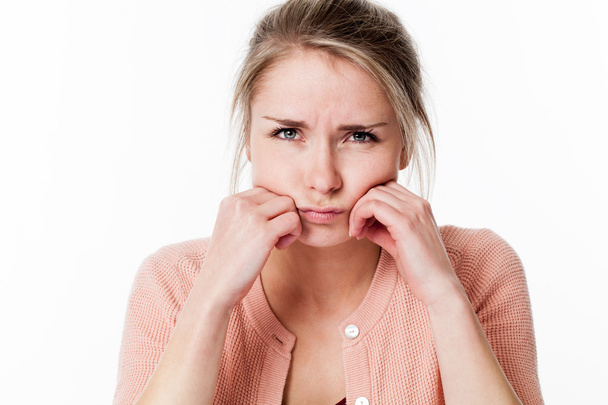 unhappy young blond woman sulking, looking offended, childish and frustrated - 写真・画像