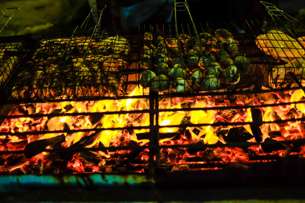 Reihe köstliche Garnelen Fisch und Muschel auf dem Grill mit Flammen im Hintergrund der Nacht - Foto, Bild