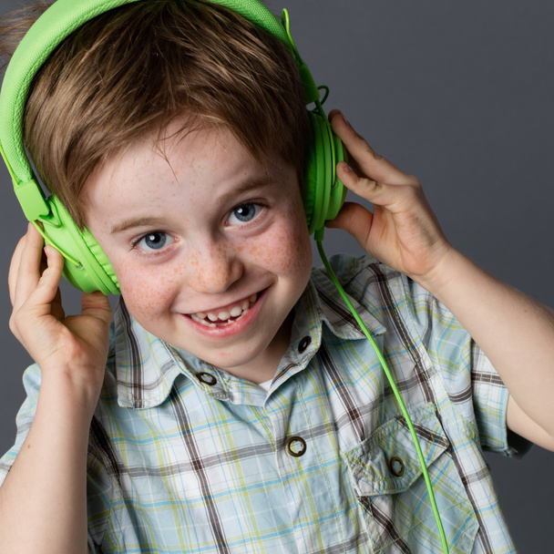 mischievous little kid with freckles laughing, listening to music - Foto, afbeelding
