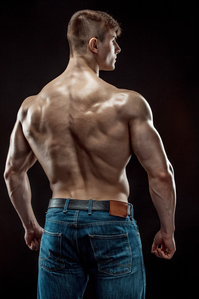 Muscular bodybuilder guy doing posing over black background - Foto, afbeelding