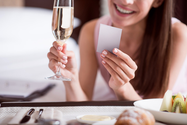 Woman looking at card and holding champagne - Foto, Imagen