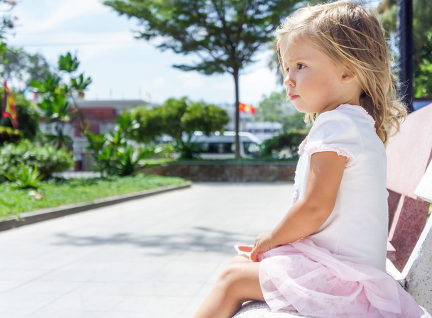 beautiful little girl sitting on the bench - Фото, изображение
