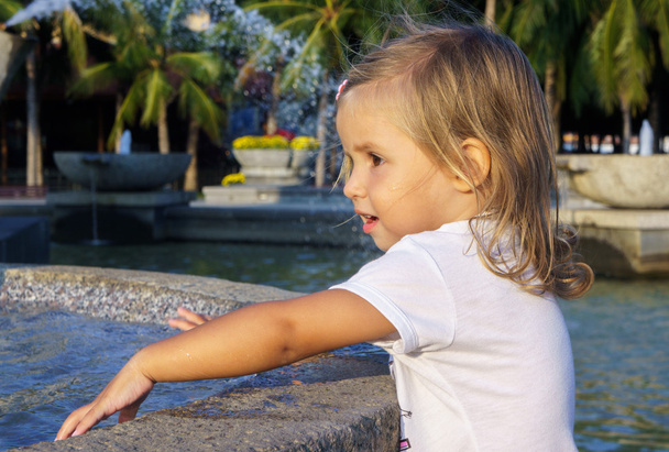 beautiful little girl washing her hands in the fountain - Photo, image