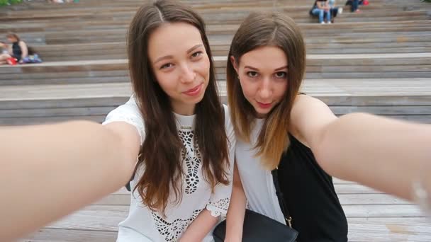 Lifestyle selfie portrait of two young positive woman having fun and making selfie. Concept of friendship and fun with new trends and technology. Best friends saving the moment with modern smartphone - Footage, Video