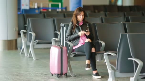 Pasajero de aerolínea en un salón del aeropuerto esperando aviones de vuelo. Mujer blanca con smartphone en la sala de espera
 - Imágenes, Vídeo