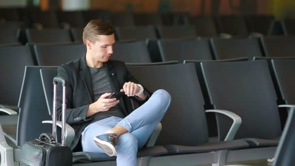 Městské obchodní muž mluví o chytrý telefon cestování uvnitř na letišti. Neformální mladý podnikatel nosit sako. Pohledný muž modelu. Mladý muž se mobil při čekání na letišti - Záběry, video