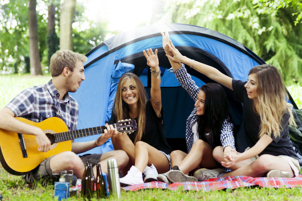 young adults have fun with guitar at the campground - Foto, Imagen