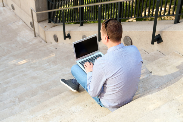бизнесмен работает с ноутбуком, сидит снаружи
 - Фото, изображение