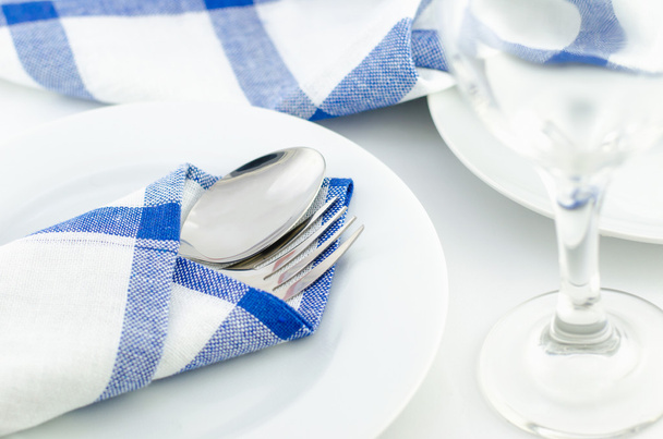 Spoon and fork at blue napkin on white plate - Фото, изображение