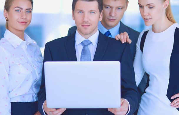 Portret van jonge zakenman in kantoor met collega's op de achtergrond - Foto, afbeelding