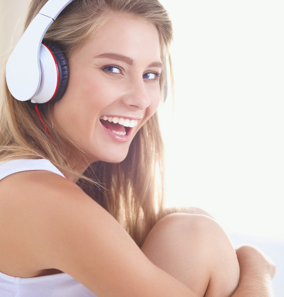 Portrait of beautiful woman in morning listening music sitting on bed at home - Photo, Image