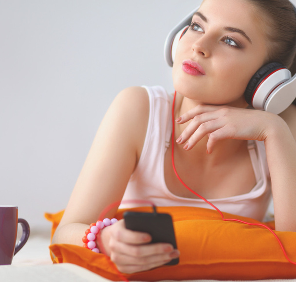 Portrait of beautiful woman in morning listening music sitting on bed at home - Фото, изображение
