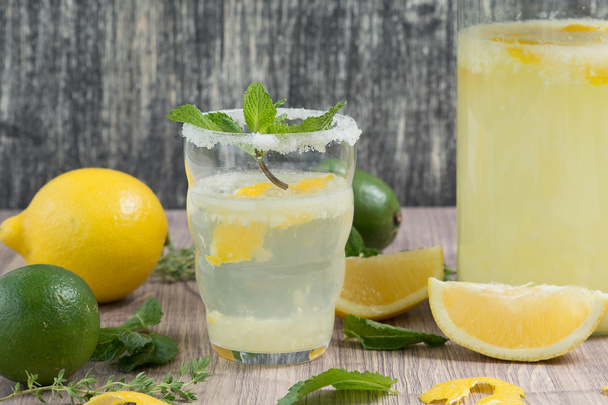 kruik en glas limonade whith munt op houten tafel - Foto, afbeelding