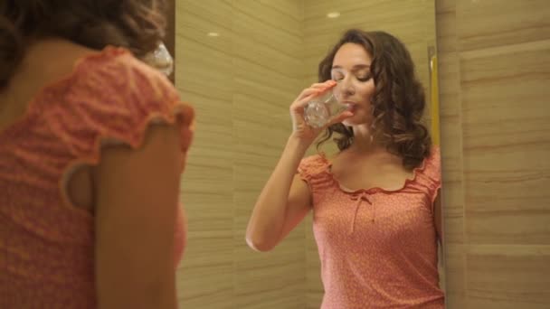Beautiful girl in a pink dress rinses her mouth in the bathroom - Video