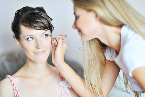 Young beautiful bride applying wedding make-up by make-up artist - Foto, Imagem
