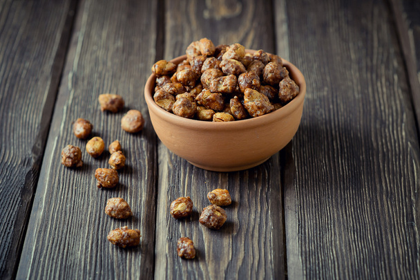 Sugared peanuts in a brown bowl on a wood background - Foto, immagini