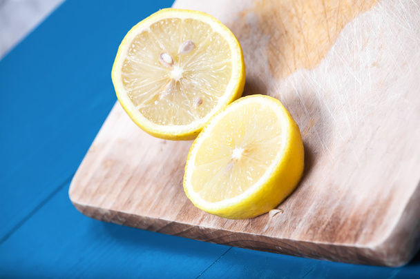 Yellow sunny half lemons blue vintage wooden background cutting  - Zdjęcie, obraz