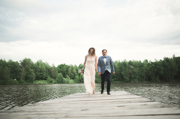 Wedding couple, bride, groom walking and posing on pier - Фото, изображение