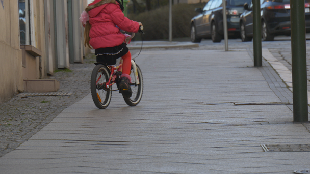 Girl is Learning to Ride Bike by City Square Opole Poland City Day Child is Riding Among Crowd of People Walking by a Street Sunny Day Springtime - Felvétel, videó