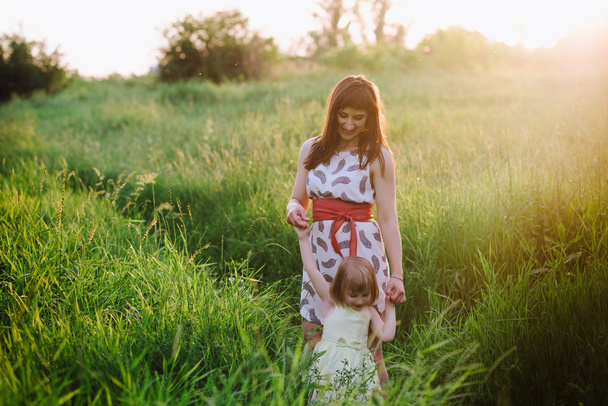 Mom and daughter dancing in nature together in sunset light - Foto, afbeelding