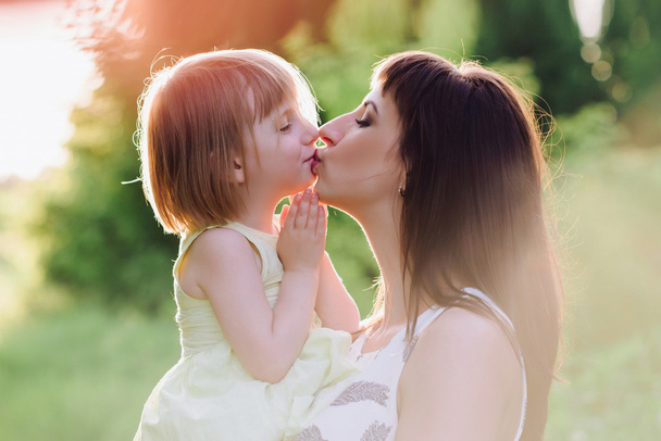 Máma líbá a objímá dcera na přírodu v sunsetlight - Fotografie, Obrázek