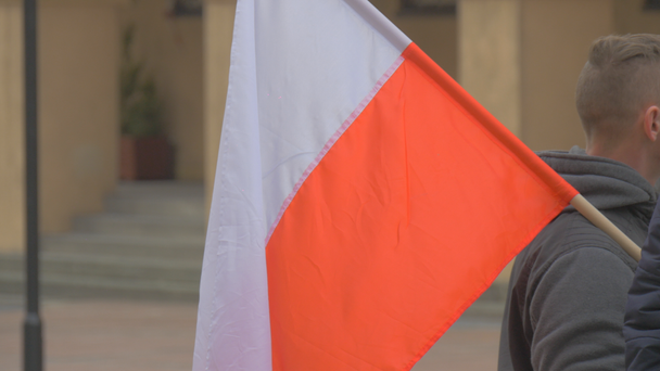 ポーランドの旗棒で年配の男性が離れて歩く男民主主義防衛委員会オポーレ市ヴィンテージ スクエアビルでポーランドの会議 - 映像、動画