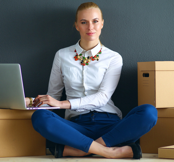 Woman sitting on the floor near a boxes  with laptop - Fotoğraf, Görsel