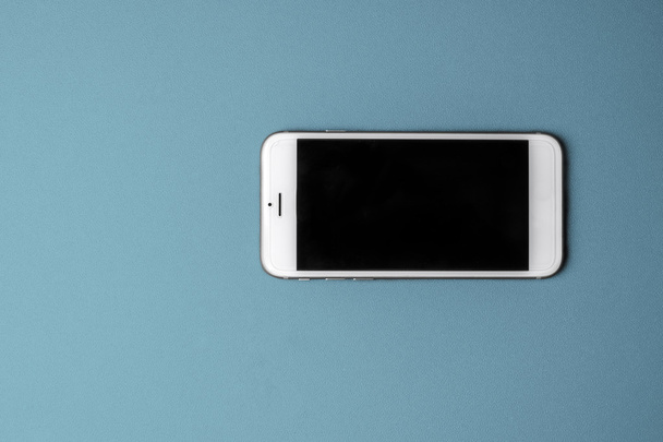 Teléfono inteligente en blanco sobre fondo azul
 - Foto, Imagen
