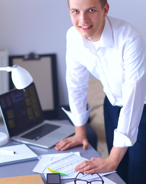 Young businessman working in office, standing near desk - Photo, Image