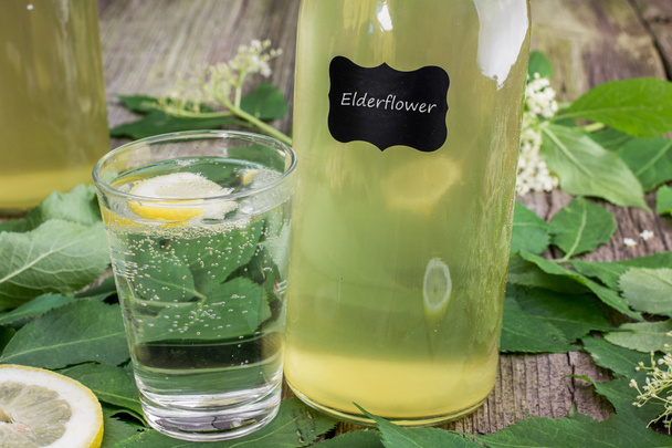 Sklenice vody s Elderflower sirupem a citronem s lahví E - Fotografie, Obrázek