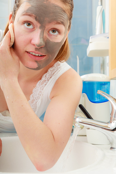 woman removing facial clay mud mask in bathroom - Foto, Imagem