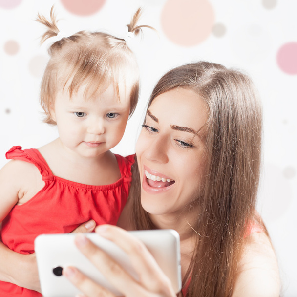 Funny baby and mother make selfie on mobile phone - Photo, image