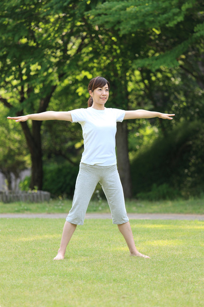 Japanese woman outside doing stretches exercise - Foto, afbeelding